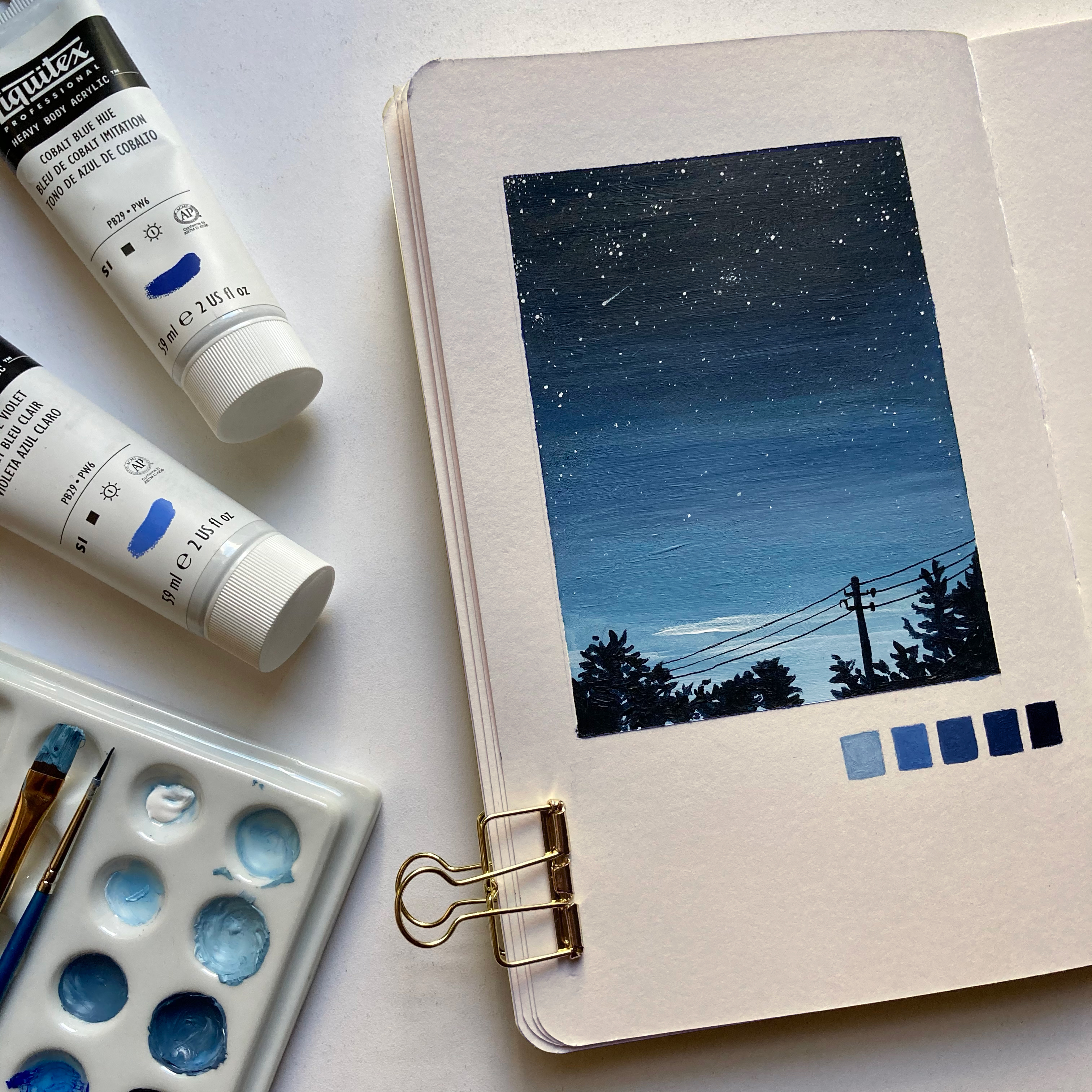 Sketchbook page showing blue sky at dusk with trees and a telephone pole silhouetted.