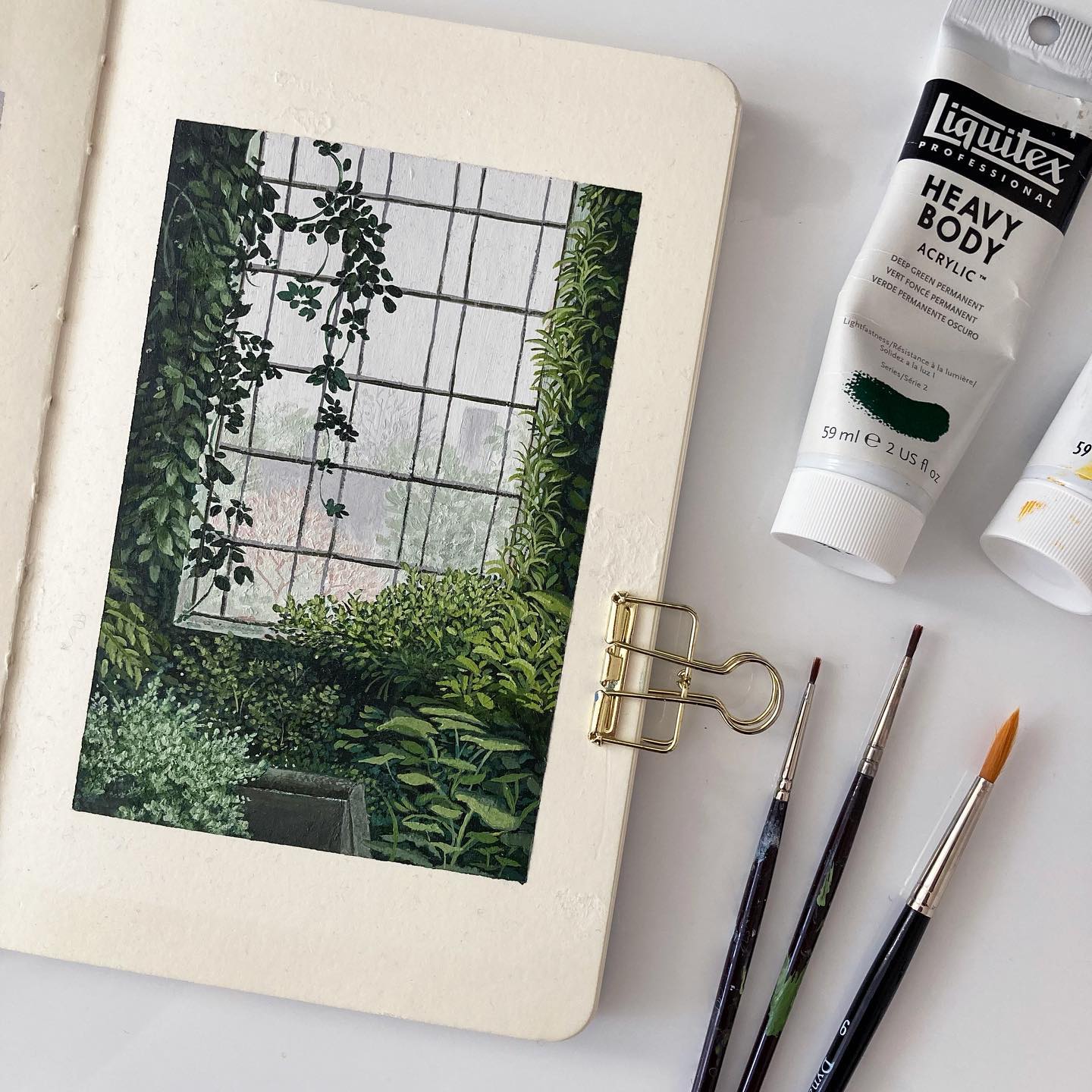 Sketchbook page showing an acrylic painting of an overgrown greenhouse.